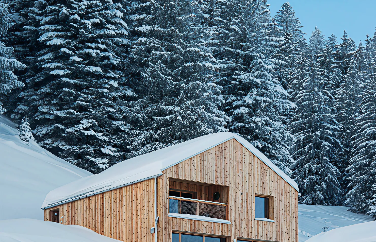 Chalet en bois sous la neige au pied d'une forêt de sapins enneigés – chalet Whitepod à louer dans le Valais