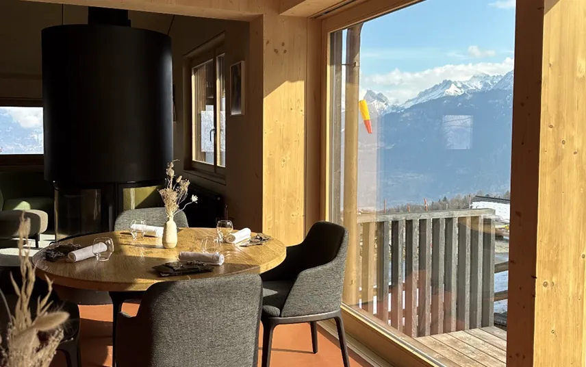 Salle à manger en bois lumineuse avec table ronde et vue sur les montagnes – restaurant Les Cerniers au-dessus de Monthey