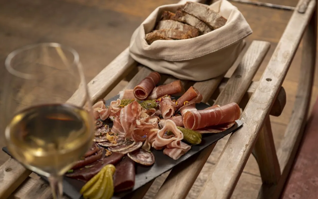 Planche de charcuterie et verre de vin blanc posés sur une luge en bois – restaurant Les Cerniers au-dessus de Monthey