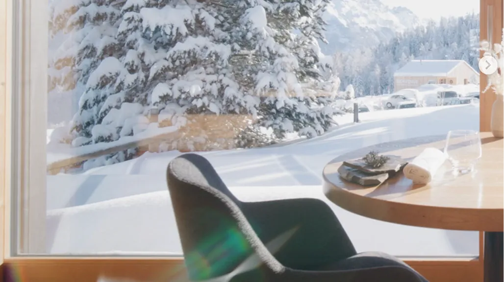 Table et chaise près d'une fenêtre donnant sur des sapins enneigés – restaurant Les Cerniers au-dessus de Monthey