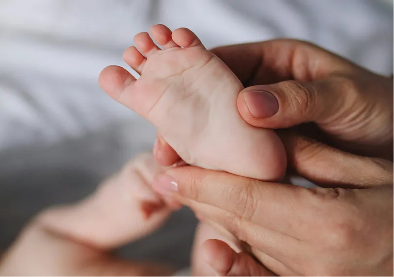 Mains massant délicatement le pied d'un jeune enfant – spa Whitepod à la montagne dans le Valais