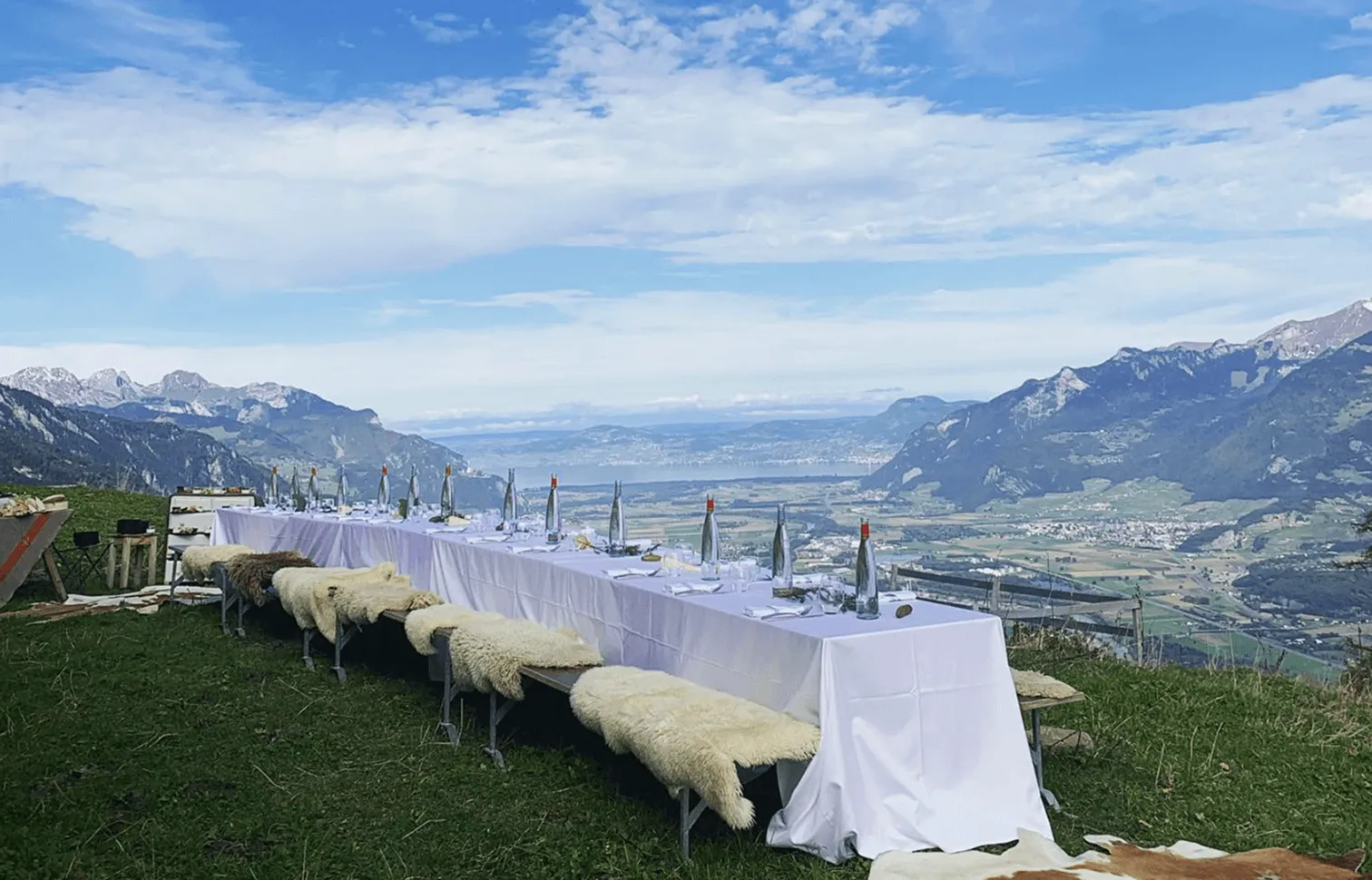 Longue table de banquet dressée en plein air face à la vallée et aux sommets – événements à Whitepod dans les Alpes suisses