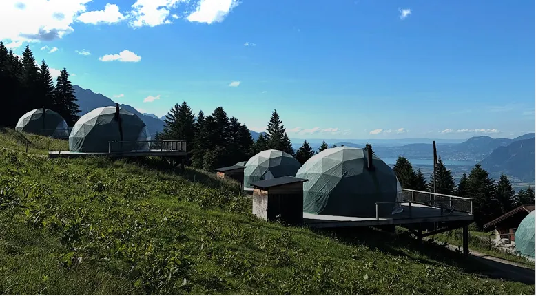 Chalets en bois sur une pente verte au crépuscule – Whitepod, hôtel insolite dans les Alpes suisses