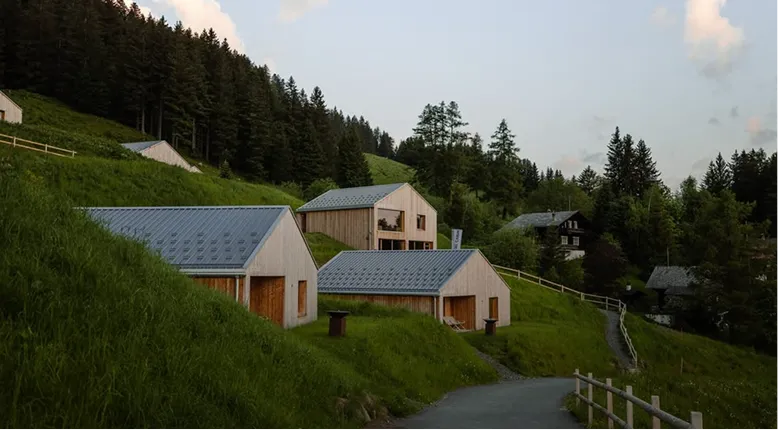 Chalets en bois sur une pente verte au crépuscule – Whitepod, hôtel insolite dans les Alpes suisses