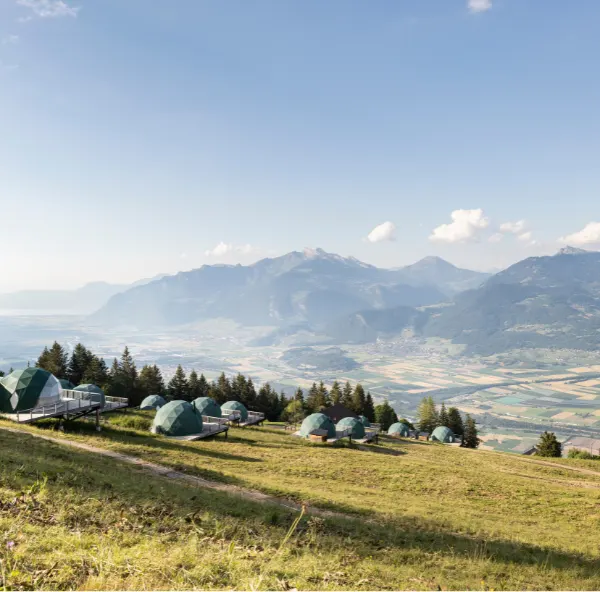 Pods dispersés sur l'alpage dominant la vallée – Elle présente les igloos de Whitepod en Suisse