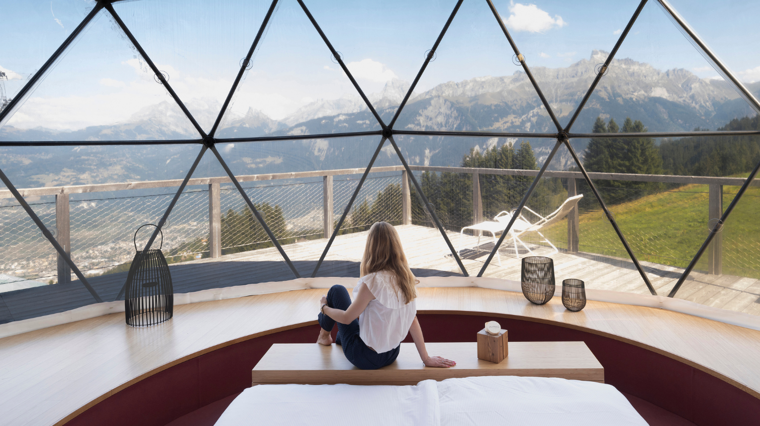 Frau am Fußende des Bettes vor der Panorama-Glaswand – Zen-Suite Pod, Pod von Whitepod in den Schweizer Alpen