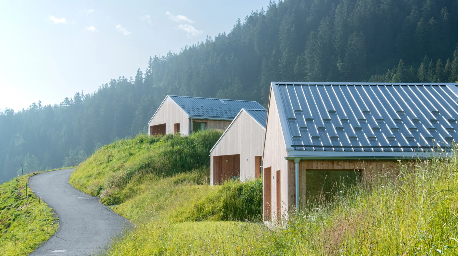 Chalets en bois aux toits métalliques le long d'un chemin de montagne – Chalet Cosy, chalet Whitepod dans le Valais