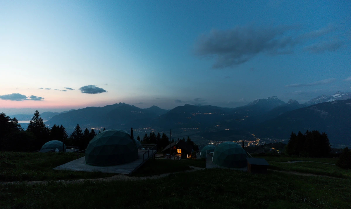 Pods en dôme sur l'alpage à la tombée de la nuit – Whitepod, hôtel bulle dans les Alpes suisses