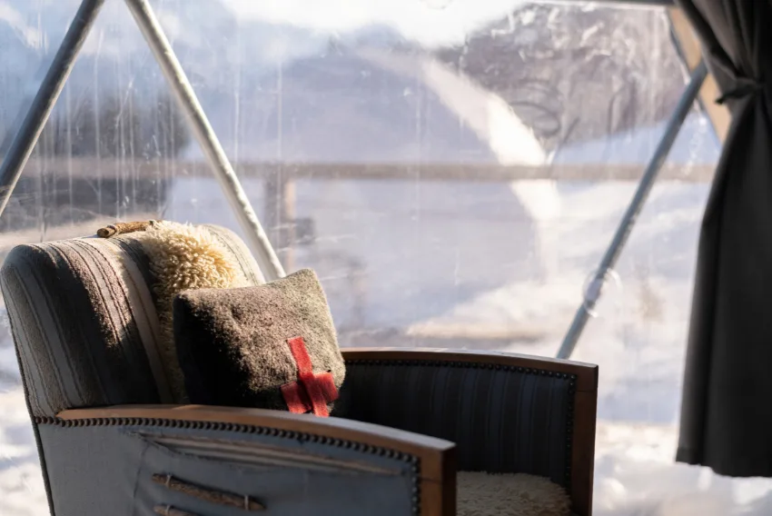 Sessel mit Schaffell vor der Glaswand eines Pods – Pod Deluxe, Pod von Whitepod im Wallis