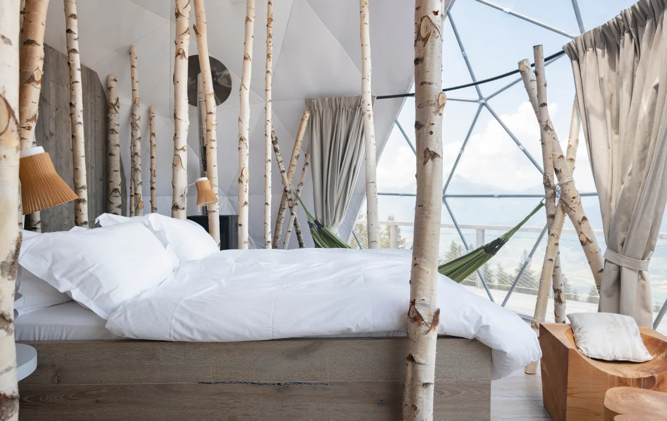 Weißes Bett, Birken und Vorhänge in der hellen Suite – Forest Pod Suite, Pod von Whitepod im Wallis