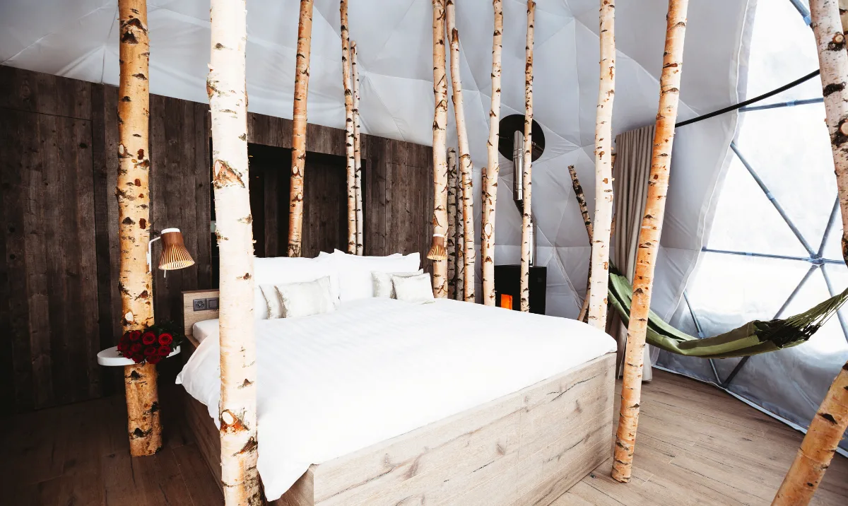 Bett und Birken unter der geodätischen Struktur der Suite – Forest Pod Suite, Pod von Whitepod im Wallis