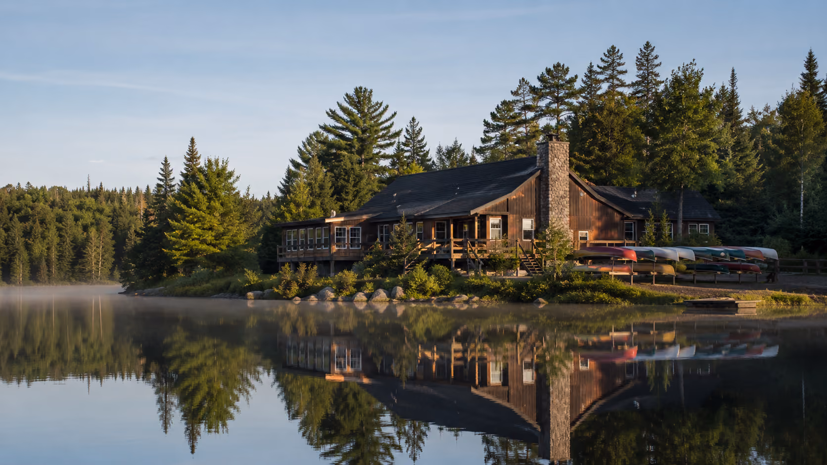 Chalet principal d'une pourvoirie au bord d'un lac en début de matinée, illustrant le marché de la revente des pourvoiries