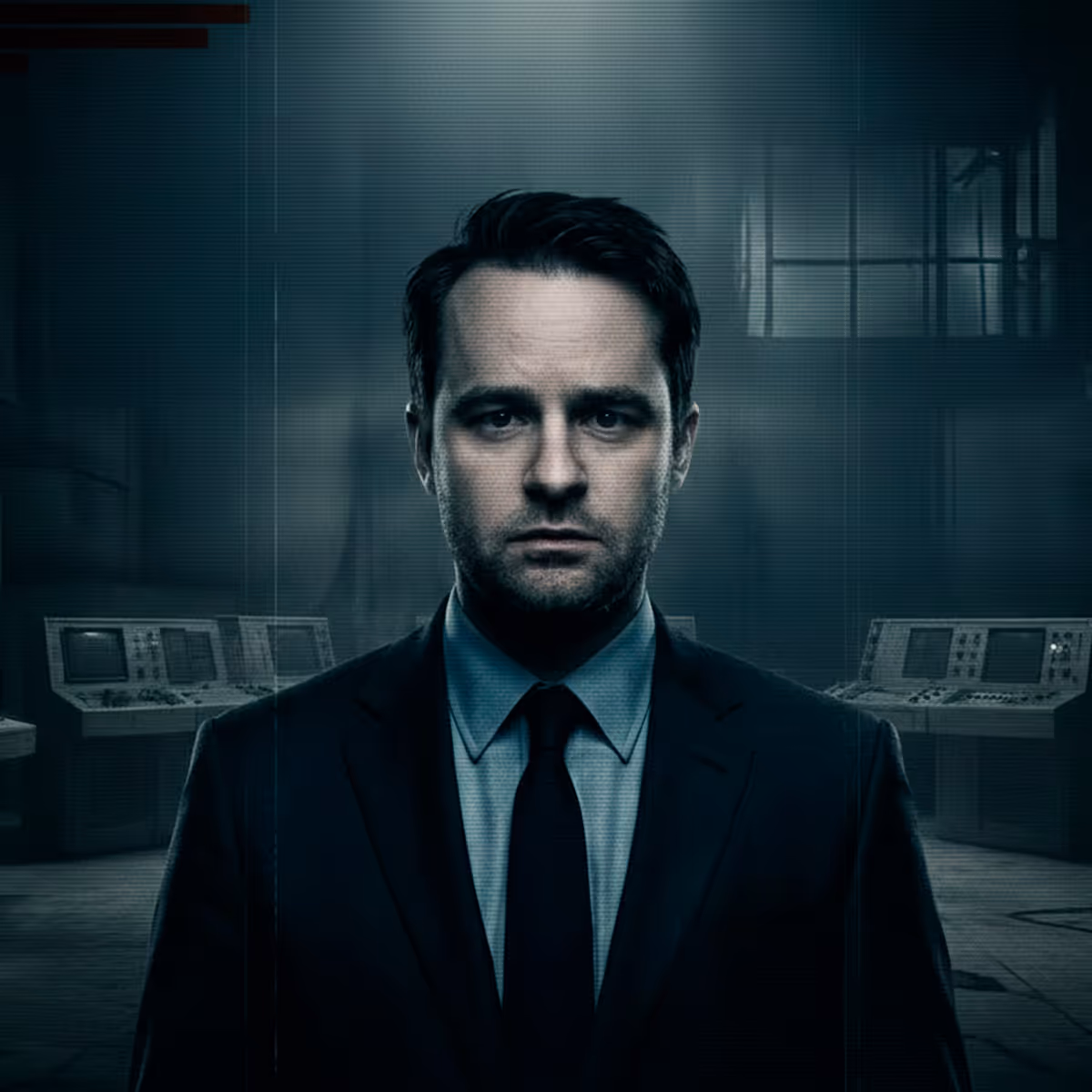 Serious man in a suit standing in a dimly lit control room with vintage monitors.