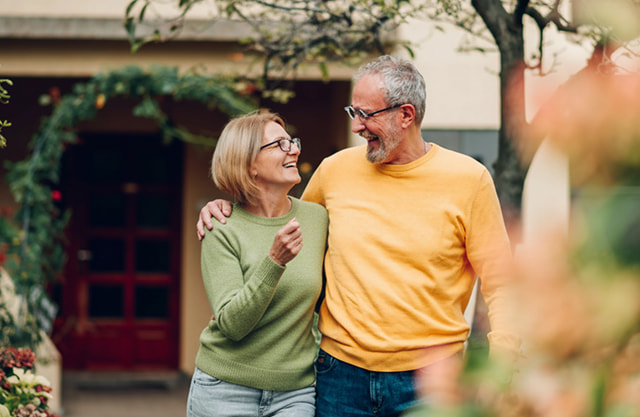 Retired couple laughing and walking through a garden