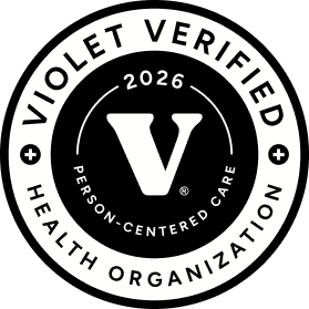 Black and white circular badge with large letter V in center, surrounded by text: '2026 Person-Centered Care' and outer ring with 'Violet Verified Health Organization'.