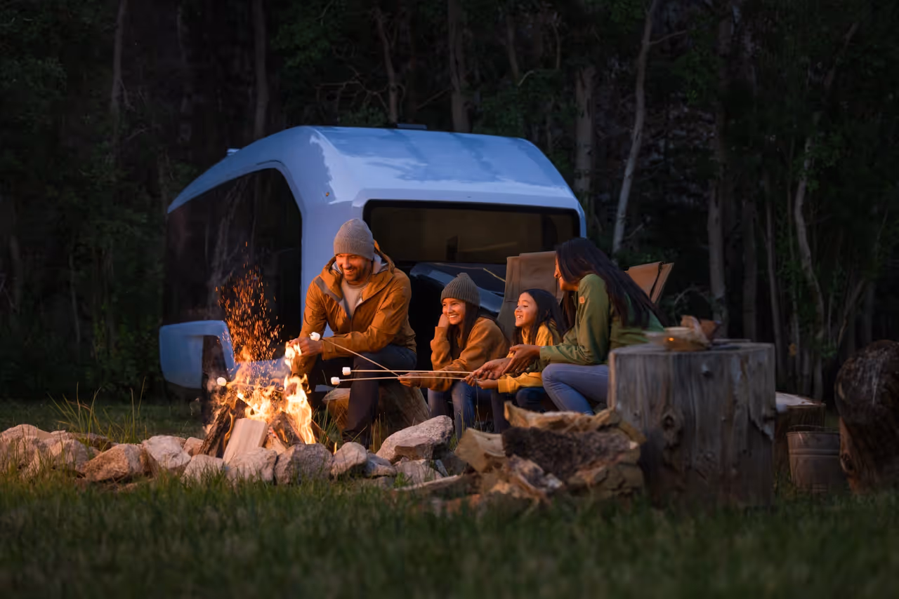 Blue SUV with open doors parked in a sunlit forest clearing with beams of light filtering through the trees.