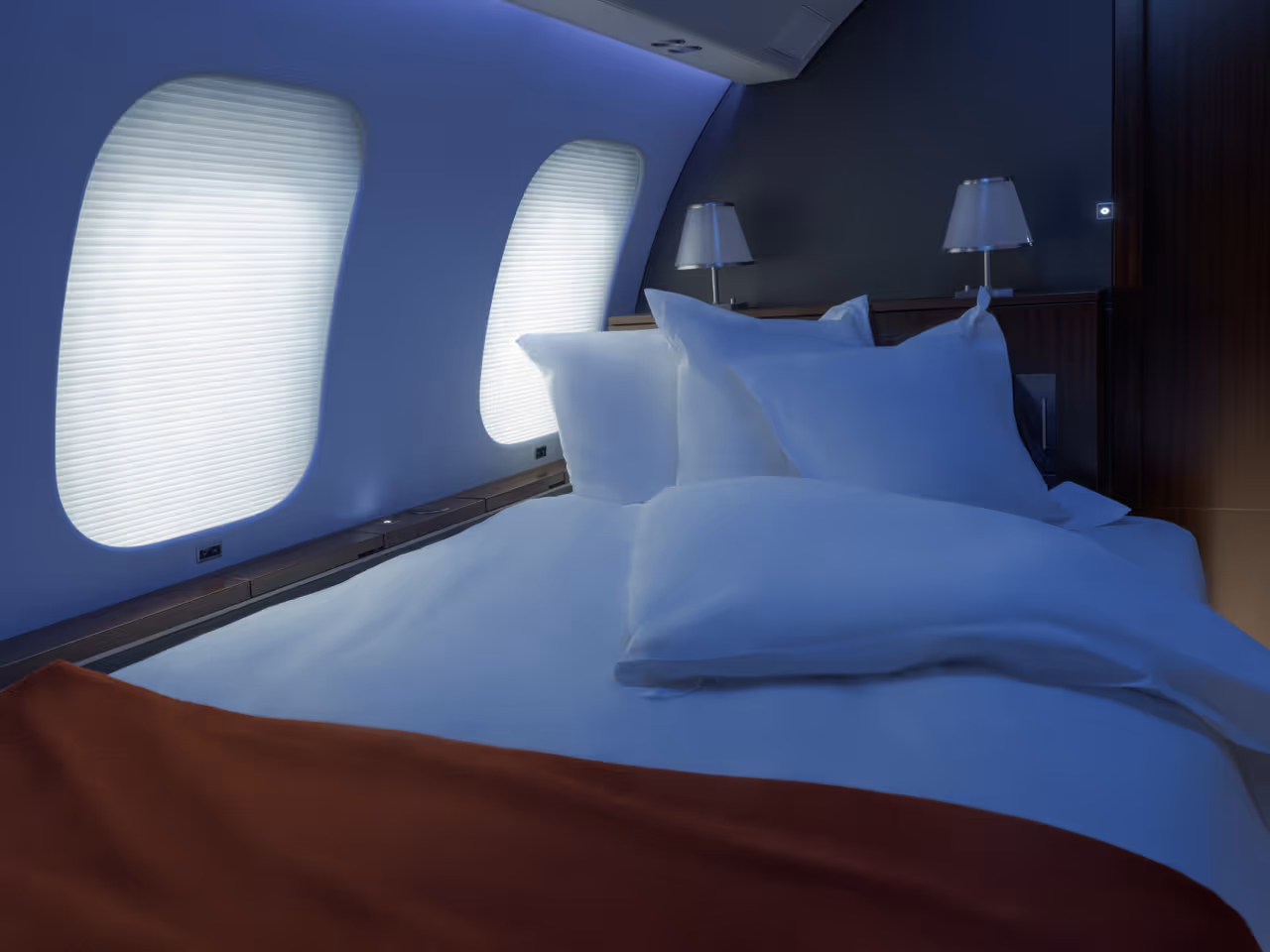 Private jet parked on tarmac at night with two people standing near the illuminated entrance stairs and a hangar labeled VISTA in the background.