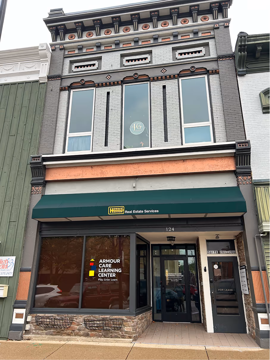 Restored historic commercial building exterior with decorative brick facade, upper level windows, and street level storefront.