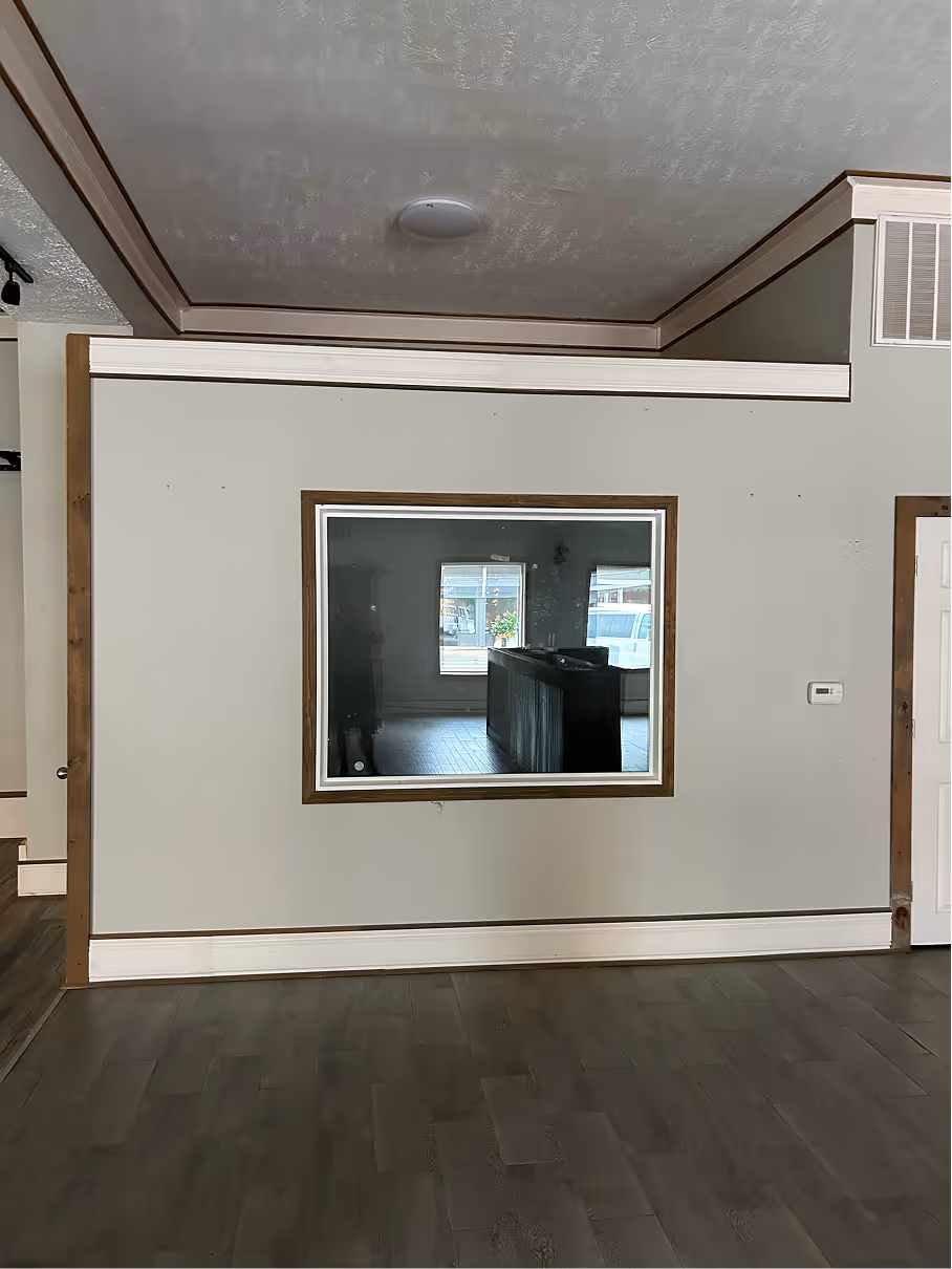Interior room before renovation with observation window, finished trim, and open connection to main space.