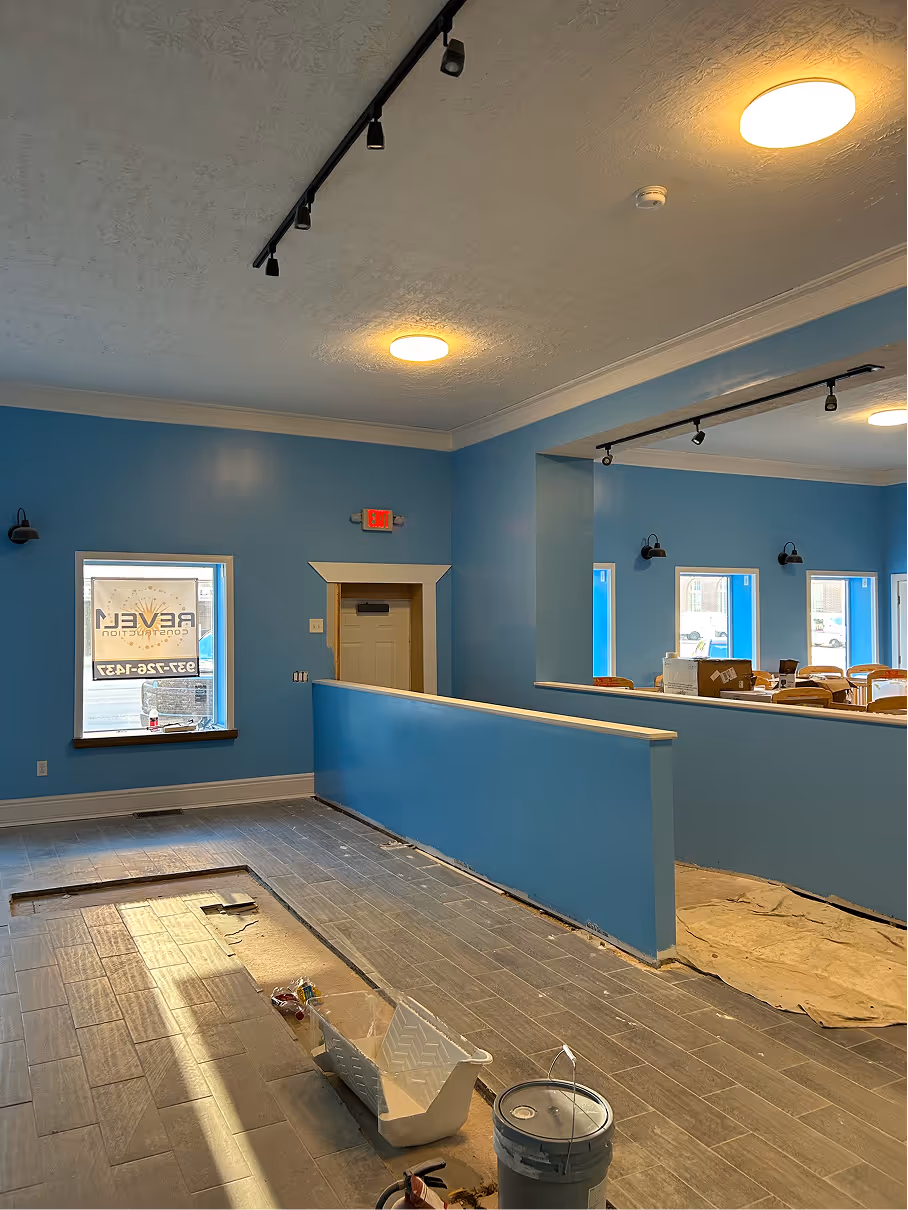 Interior daycare space mid-renovation with blue walls, exposed framing, and unfinished flooring.