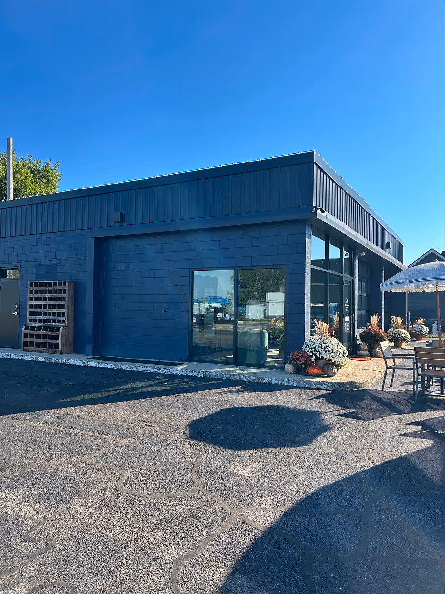 Finished exterior of commercial building with dark metal siding, large glass windows, and outdoor seating area.
