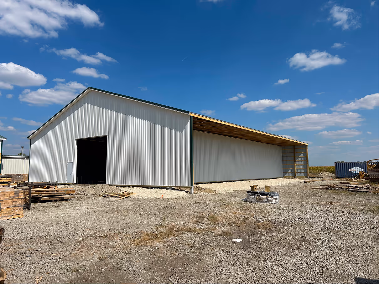 Front angle of metal-sided industrial building with open bay door and extended side overhang.