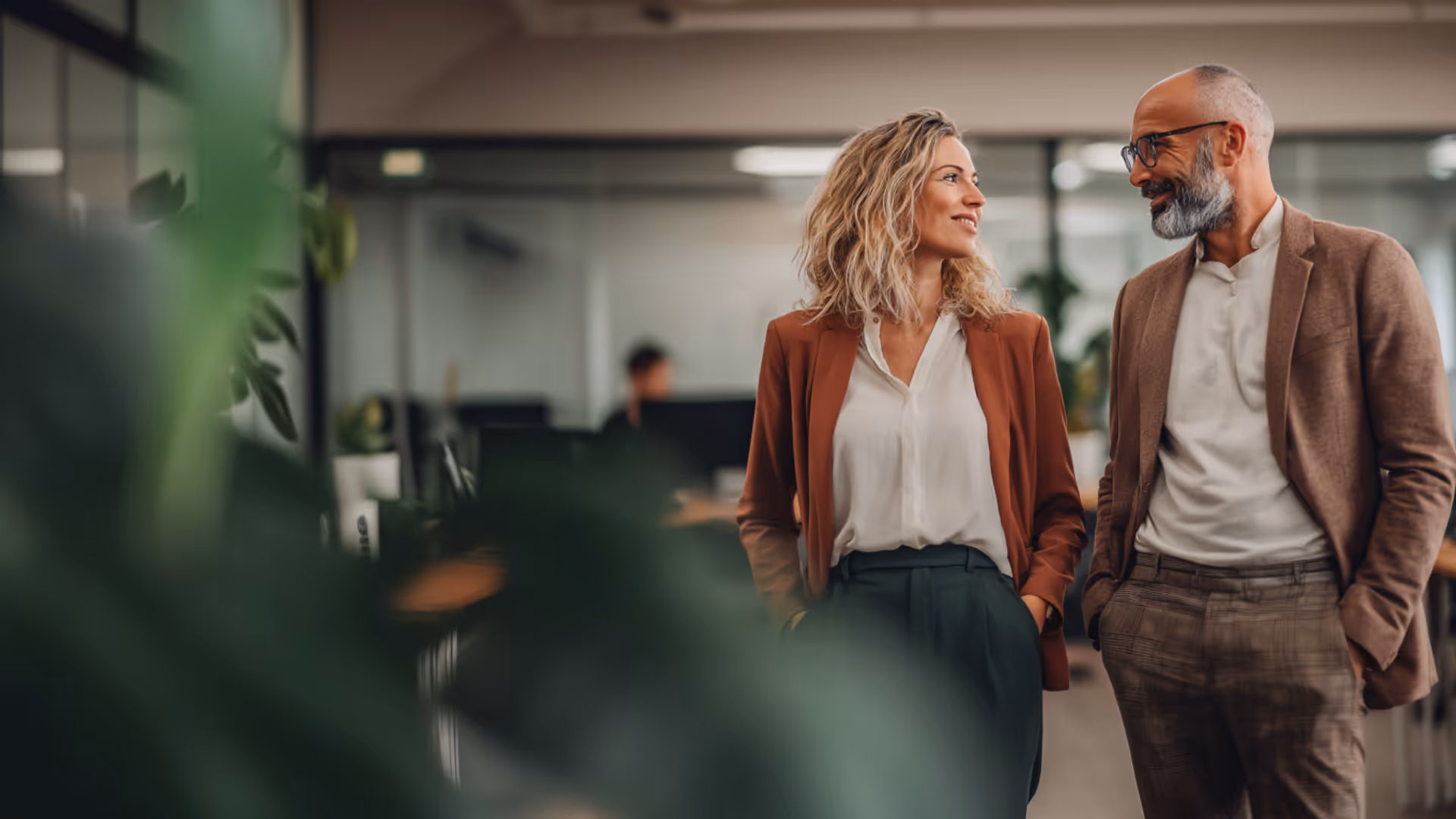 Smiling middle-aged man and woman walking and talking together in a modern office.