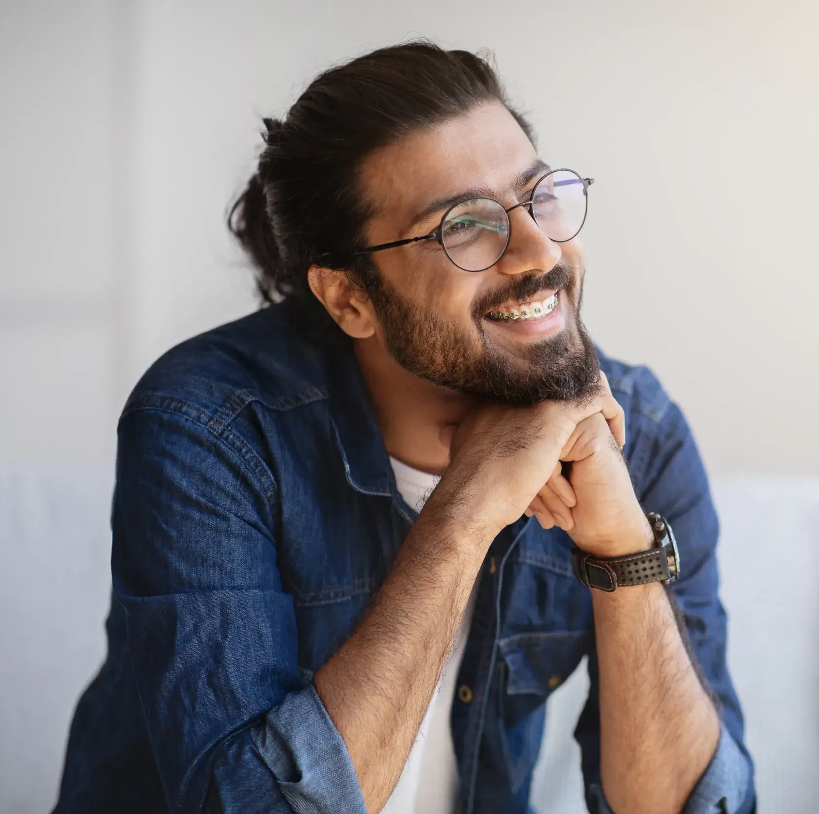 A man with a beard and glasses sitting on a couch.