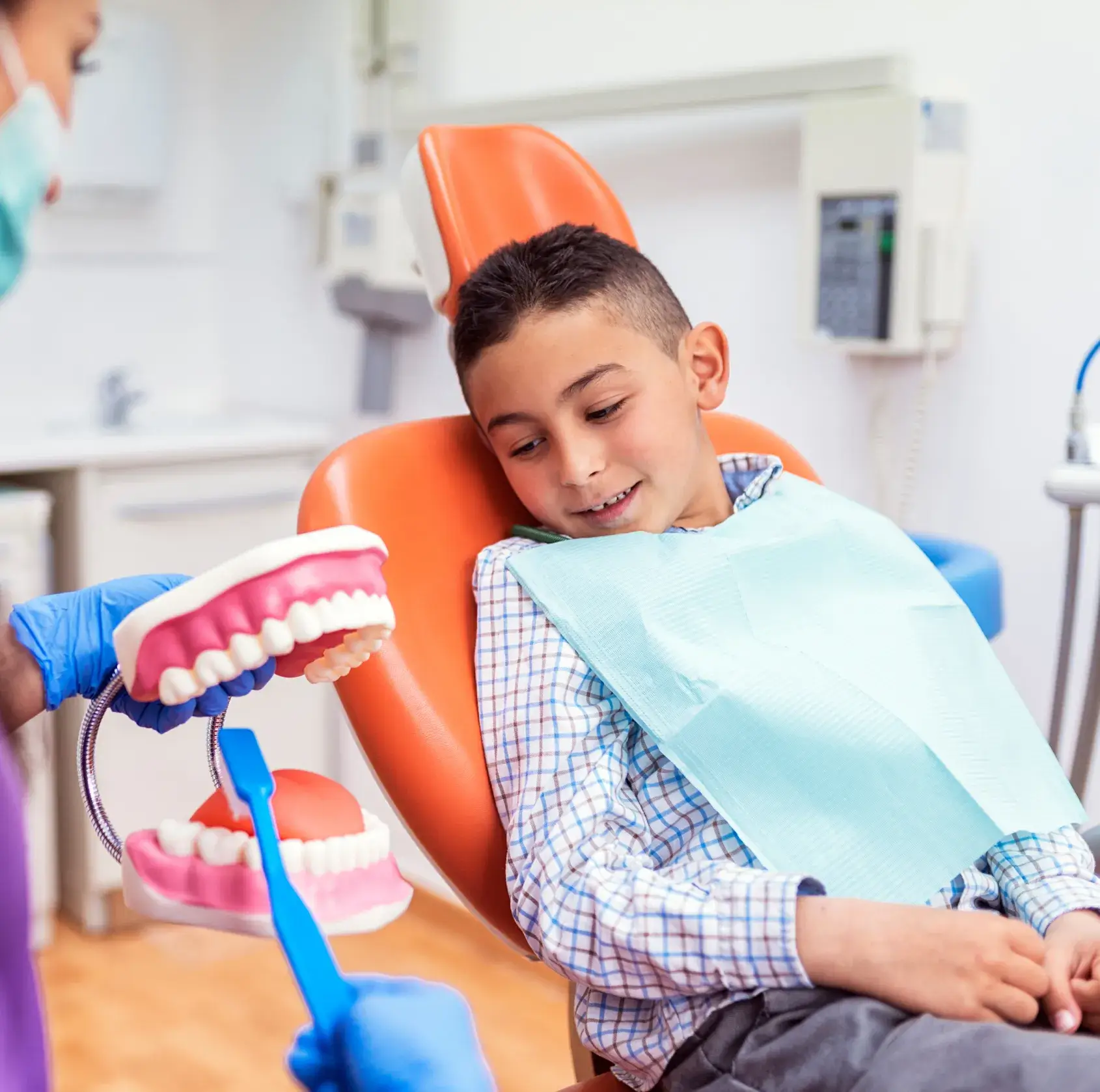 A young boy getting his teeth checked by a dentist.