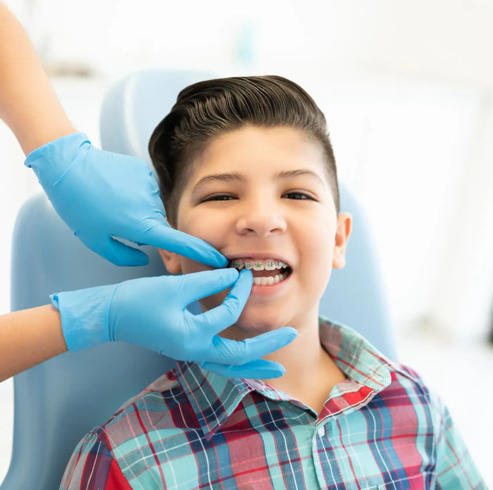A young boy getting his teeth brushed by a dentist.