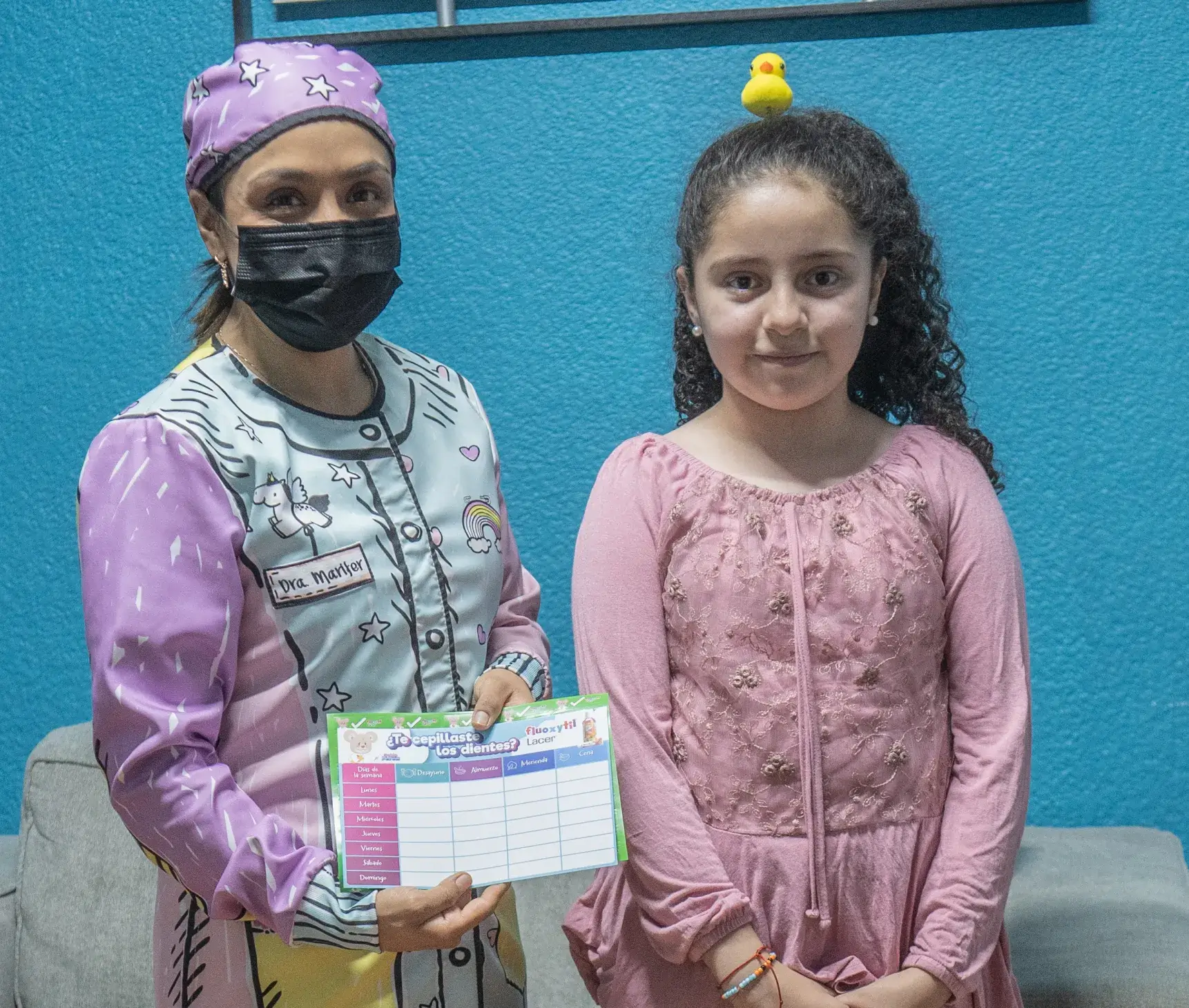 Dentista y paciente pediatrico mostrando una cartilla dental