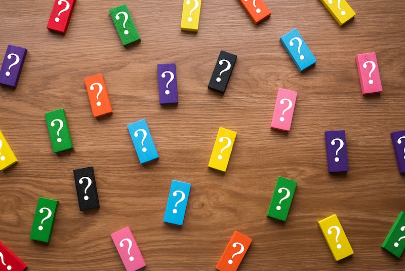 Colorful wooden blocks with a symbol of question mark on wooden background.