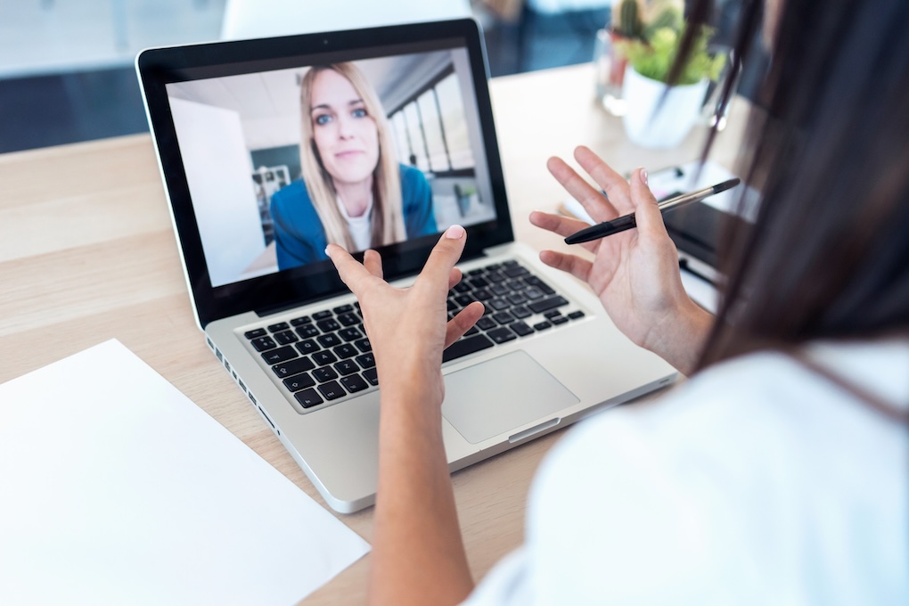 Shot of back view of a person talking to a woman a video call with the laptop at home.