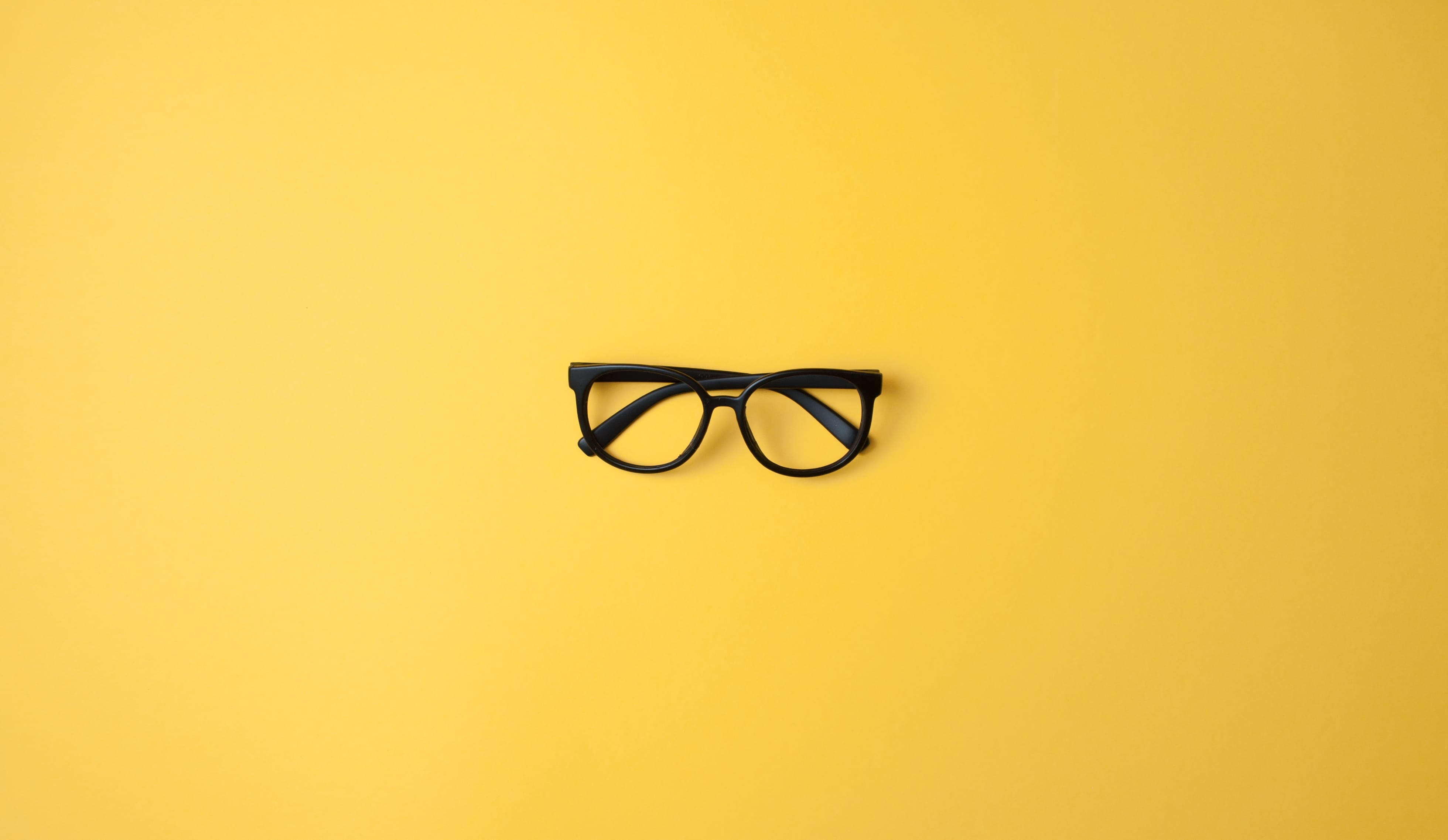 black framed glasses on a plain yellow background