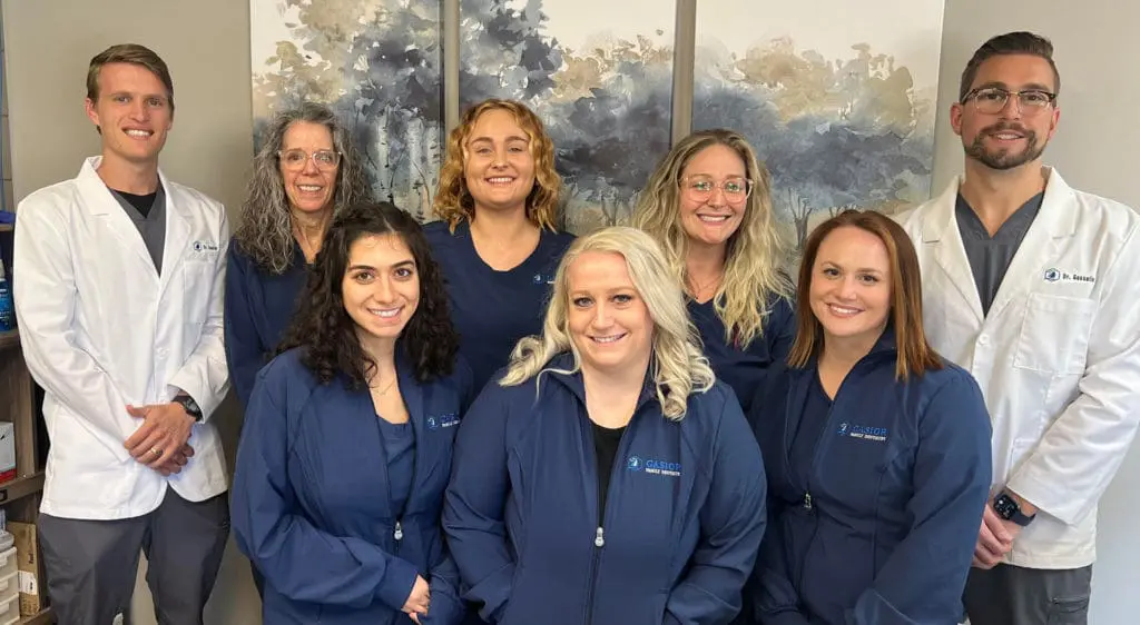 The team at Gasior Family Dental in Northville, MI poses together in a professional group portrait, smiling warmly. The image reflects a collaborative, family-oriented dental practice made up of experienced dentists, hygienists, and support staff dedicated to providing high-quality, compassionate care for patients of all ages.