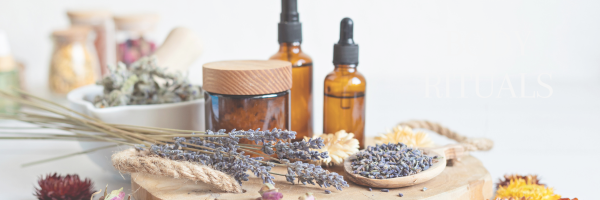 Amber glass dropper bottles, a wooden jar, dried lavender, and a wooden spoon with dried lavender arranged on a wooden surface.