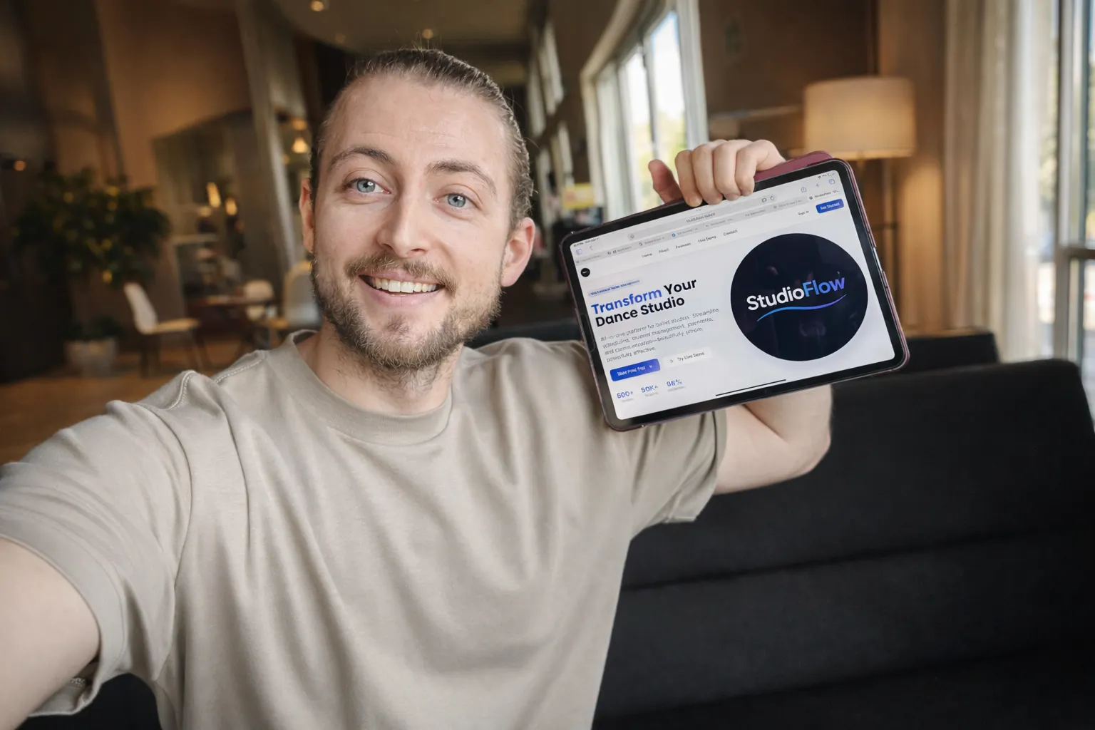 Ivan holding a laptop while smiling, wearing casual clothes, against a neutral background