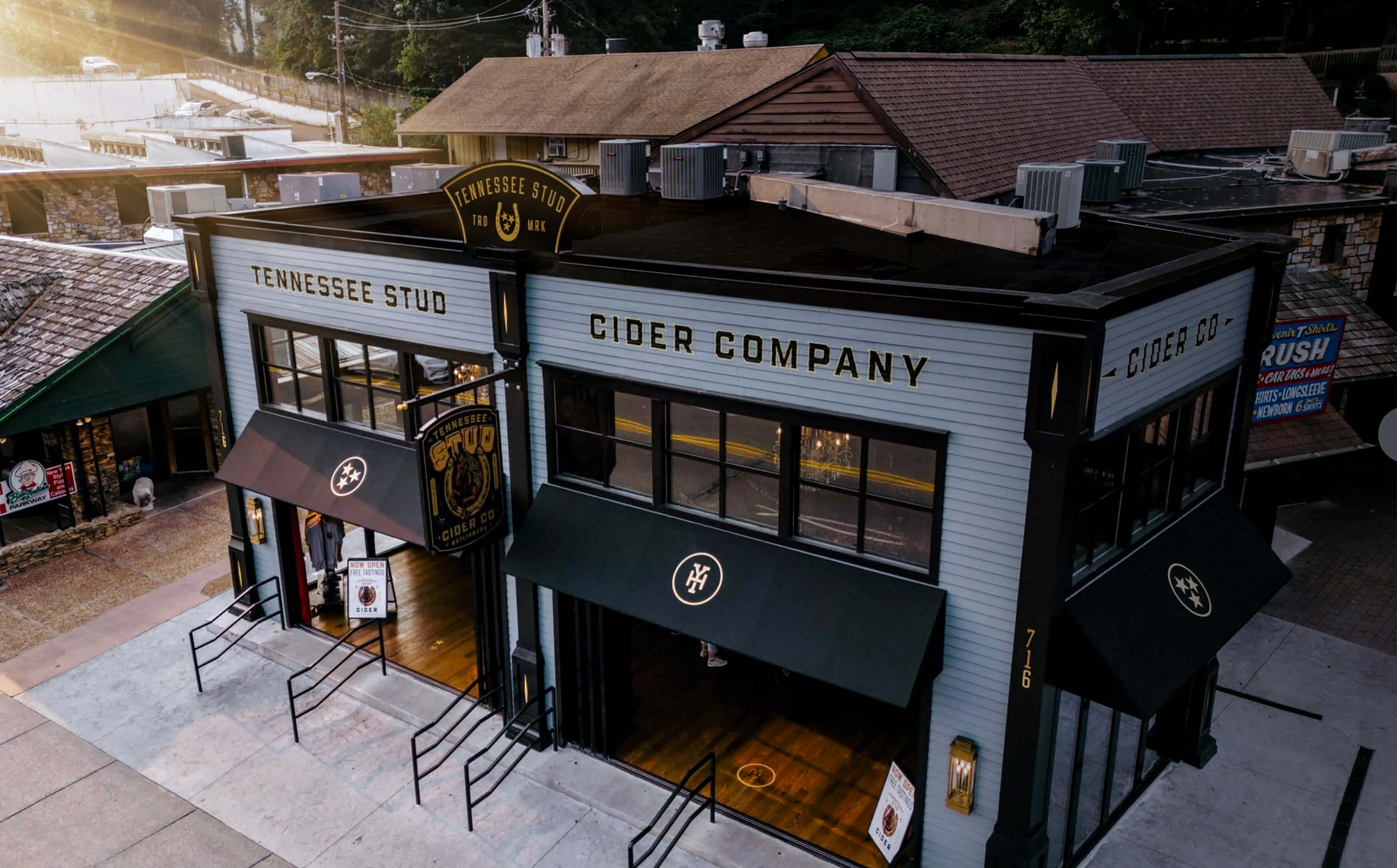 Building exterior of Tennessee Stud Cider Company with black and white facade, black awnings, and signage displaying the company name, located at street corner in daylight.
