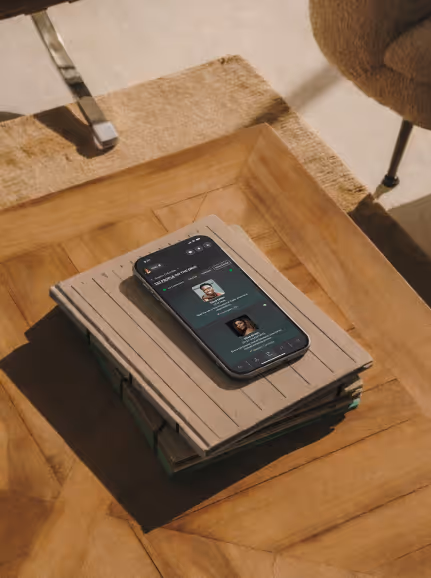 Smartphone displaying a messaging app screen, resting on a stack of notebooks on a wooden table.