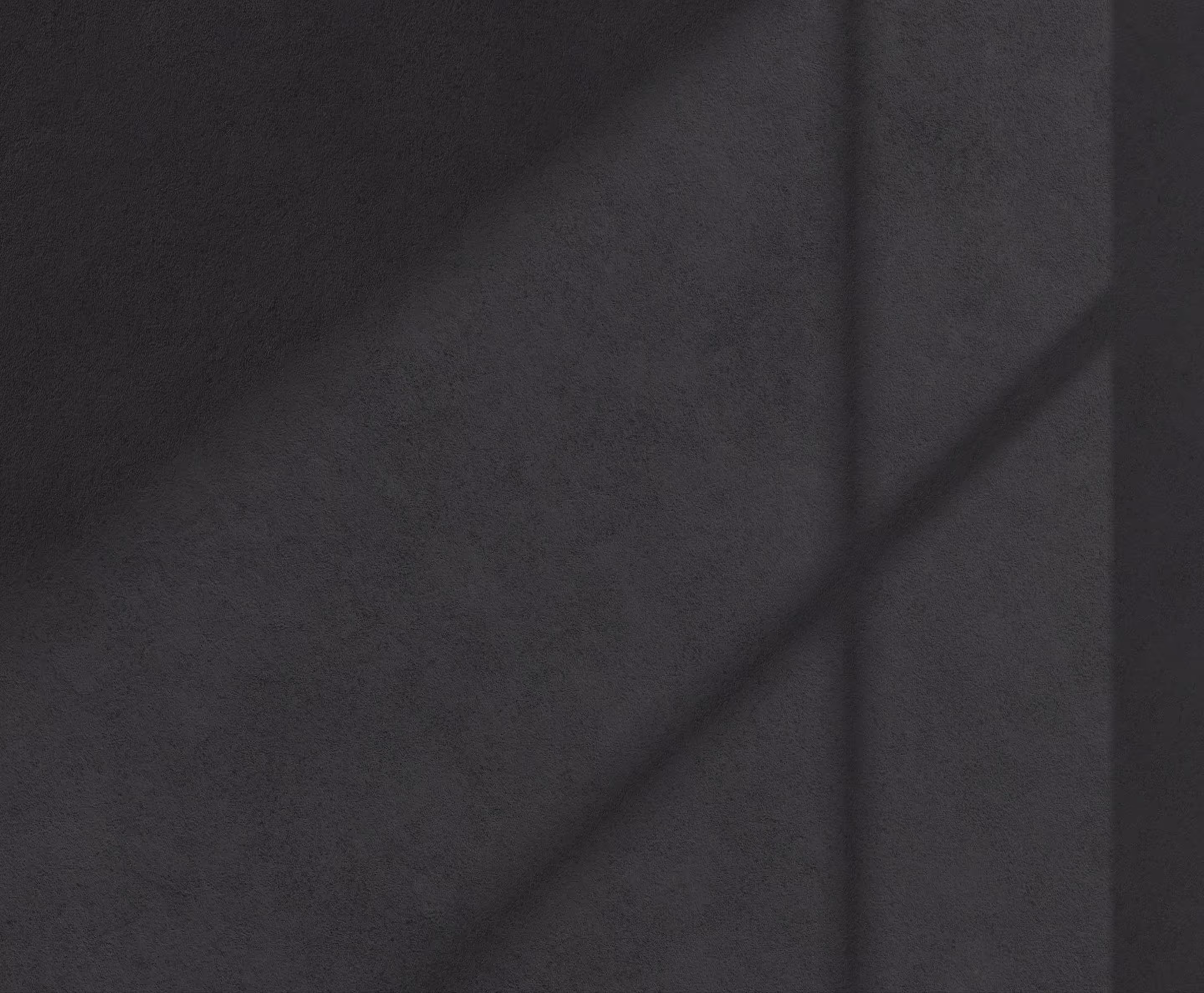 Dark textured surface with soft shadows forming diagonal lines.