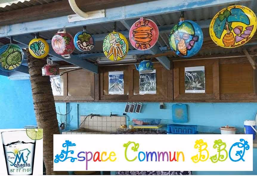 Outdoor kitchen area with colorful painted lanterns hanging from a roof beam and a blue wall with wooden cabinets in the background.