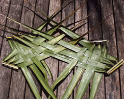 Two woven palm leaf mats on a wooden surface.