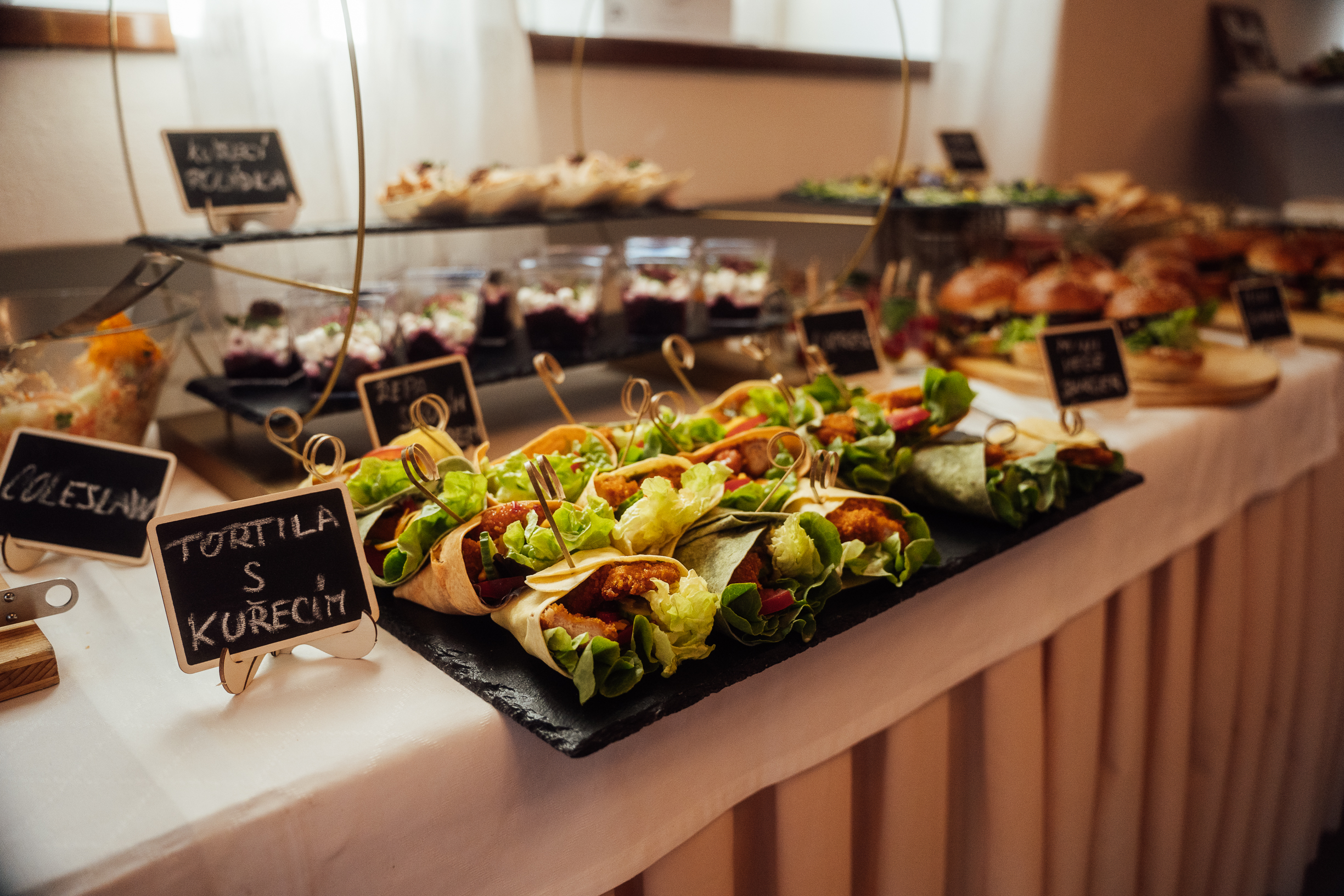 Stůl s různými druhy předkrmů, včetně tortill s kuřecím masem a zeleninou.