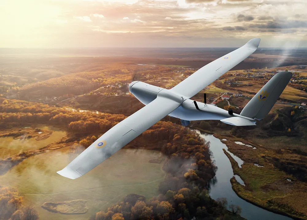 White drone flying over a river and forest landscape during sunset.