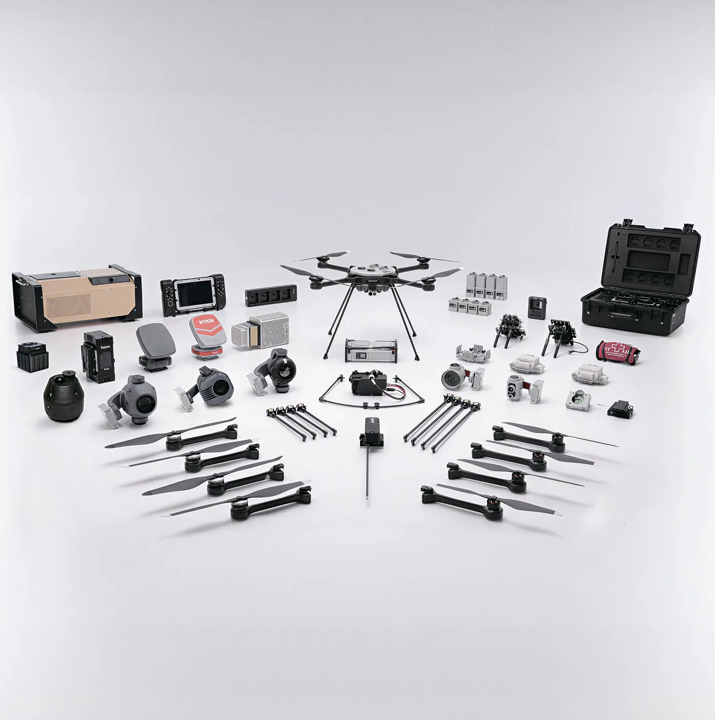 Disassembled drone kit with eight rotor arms, multiple cameras, batteries, electronic components, and a carrying case on a white background.