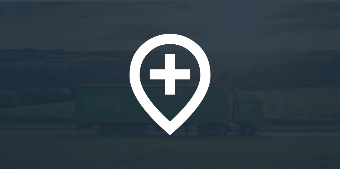 White location pin icon with a plus sign inside on a blurred background of a green truck on a road.