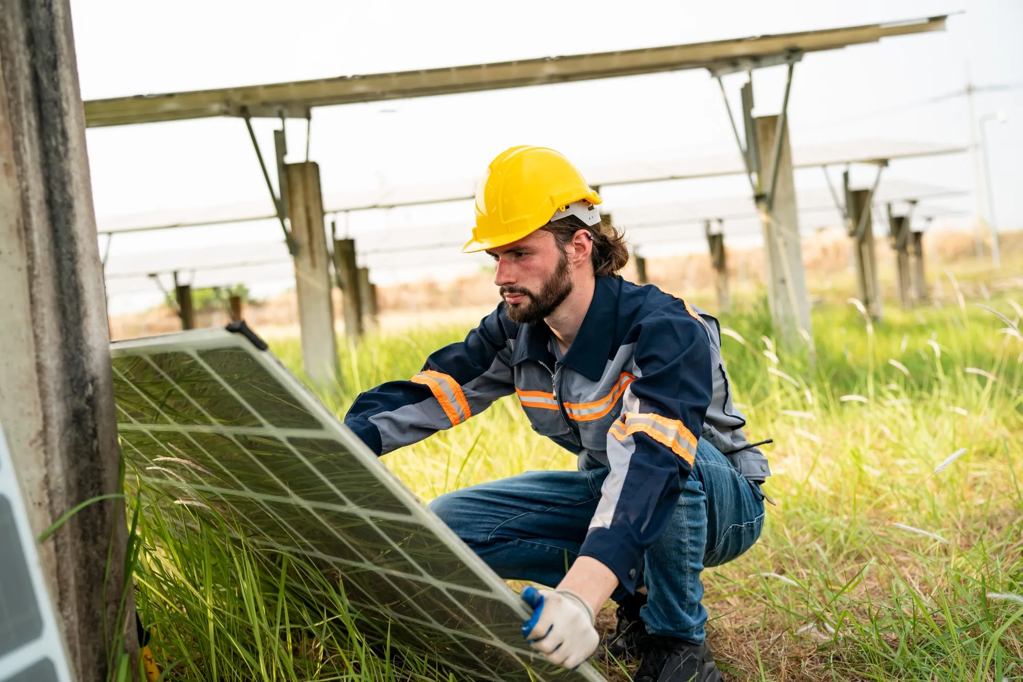 Engineer in safety gear removing a solar panel from mounting structures on a solar farm