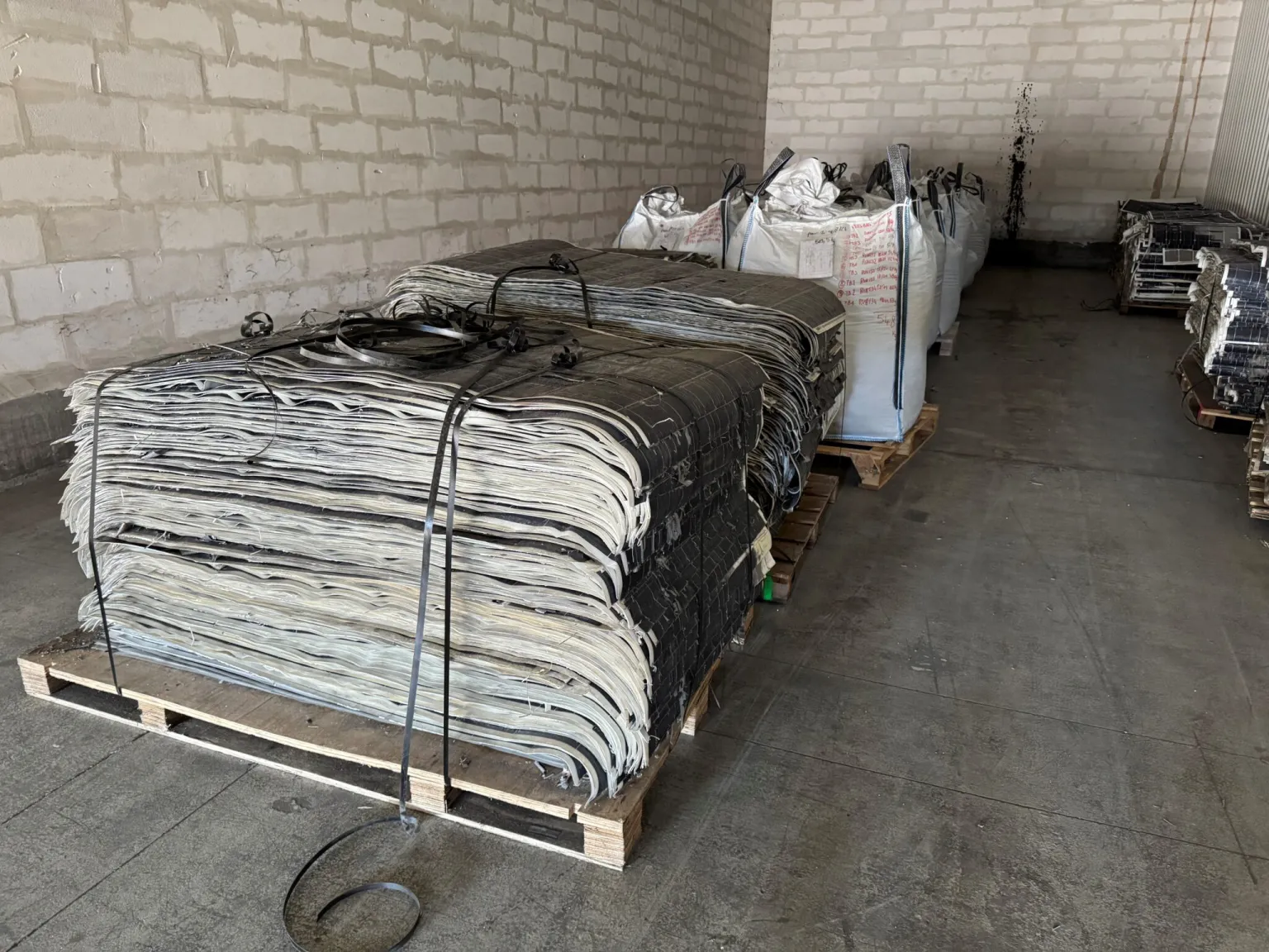 Decommissioned solar panels stacked on pallets at a recycling facility awaiting processing