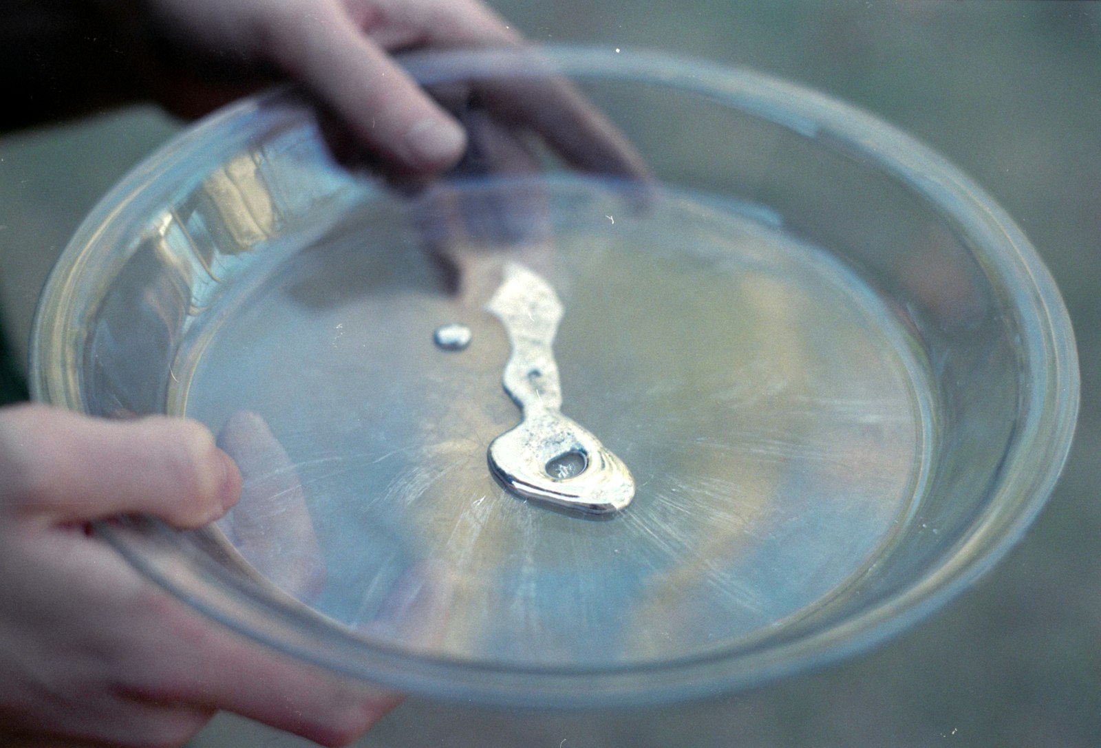Liquid metal in a glass dish, illustrating the mercury content recovered from fluorescent tubes