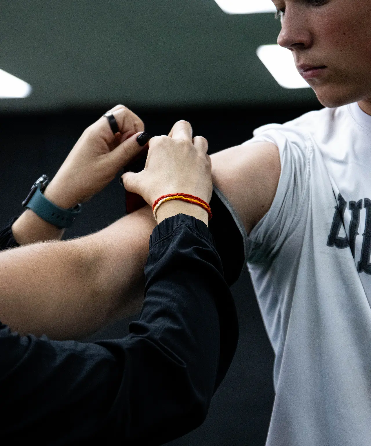 Person in white shirt receiving an injection in the upper arm from another person.